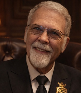 Mark Williams smiling, wearing glasses and a formal jacket